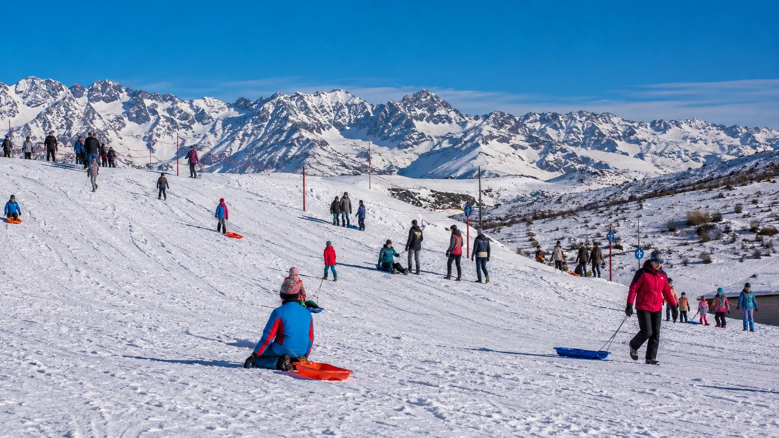 Familias jugando con trineos en una ladera nevada de Mendoza
