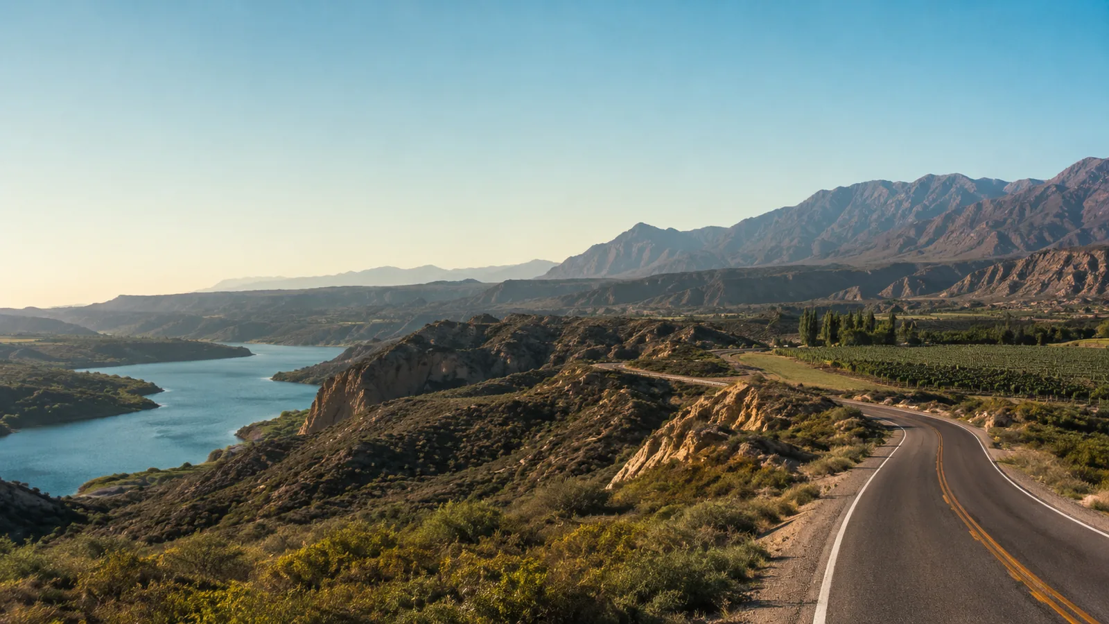 Paisaje editorial de la Zona Sur de Mendoza con lago, ruta y montañas